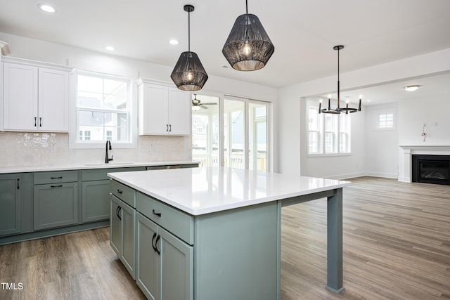 kitchen with a wealth of natural light, light countertops, a glass covered fireplace, a sink, and light wood-type flooring