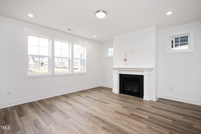 unfurnished living room with visible vents, a fireplace, baseboards, and wood finished floors