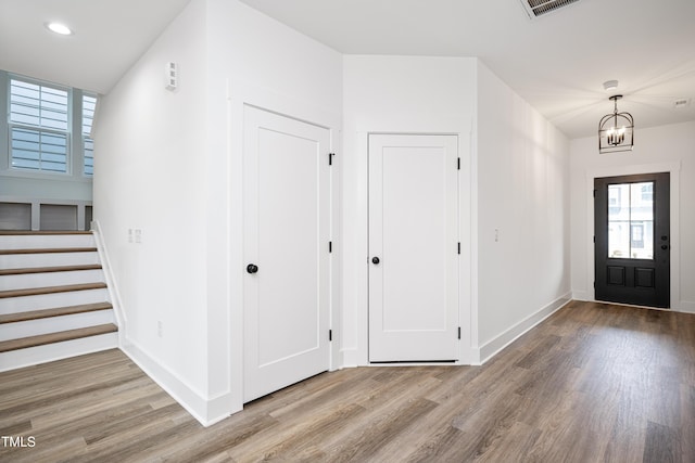 foyer featuring baseboards, wood finished floors, an inviting chandelier, stairs, and recessed lighting