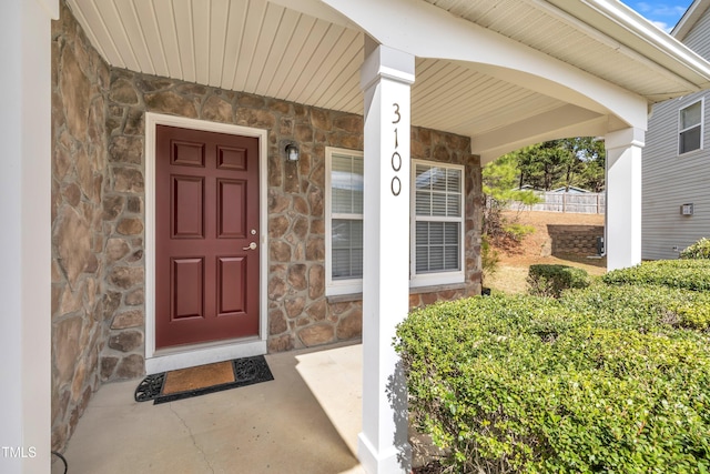 entrance to property featuring covered porch and stone siding