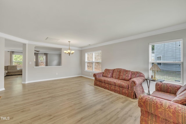 living room with plenty of natural light, light wood-type flooring, a notable chandelier, and crown molding