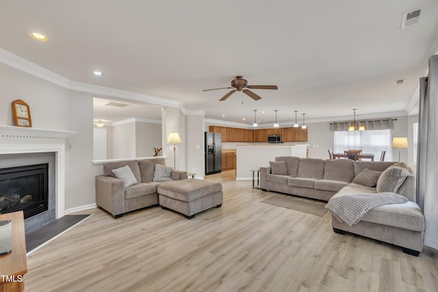 living area featuring a glass covered fireplace, visible vents, and light wood-style flooring