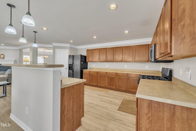 kitchen featuring ornamental molding, light countertops, appliances with stainless steel finishes, and light wood-style floors