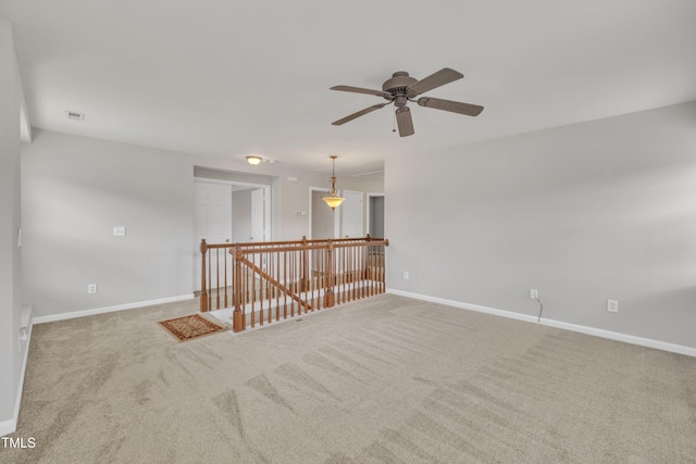 carpeted spare room with ceiling fan, visible vents, and baseboards