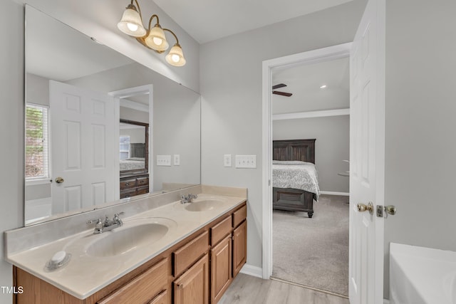 ensuite bathroom featuring ensuite bathroom, double vanity, a sink, and a bathtub