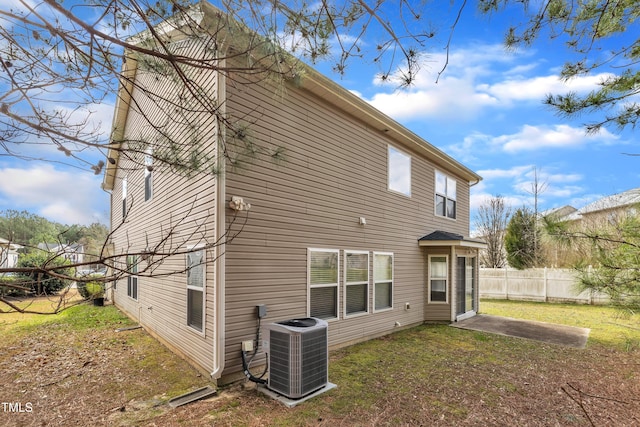 back of property with a lawn, fence, and central AC