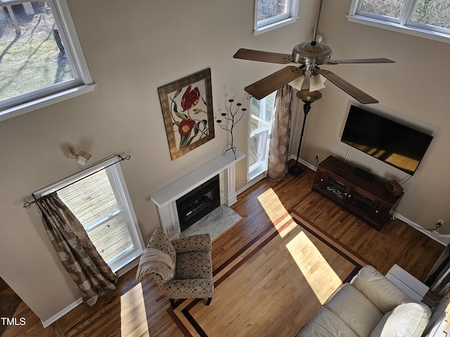 living room with a fireplace with flush hearth, wood finished floors, and a towering ceiling