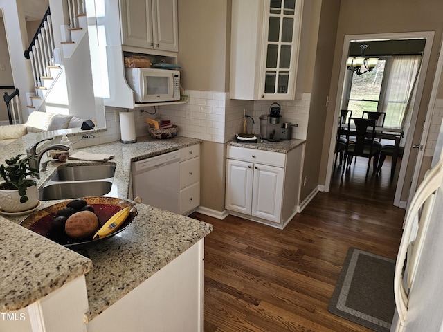 kitchen with a sink, white appliances, dark wood-style flooring, and light stone countertops