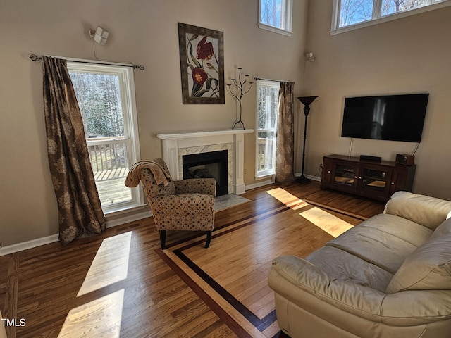 living room with a high end fireplace, baseboards, a wealth of natural light, and wood finished floors