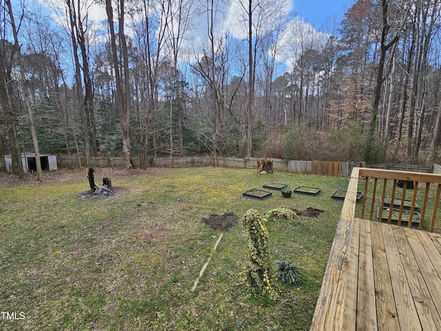 view of yard featuring a deck, a forest view, and a fenced backyard