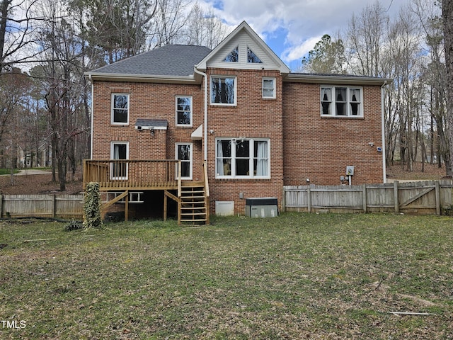 rear view of house featuring a lawn, brick siding, and a fenced backyard