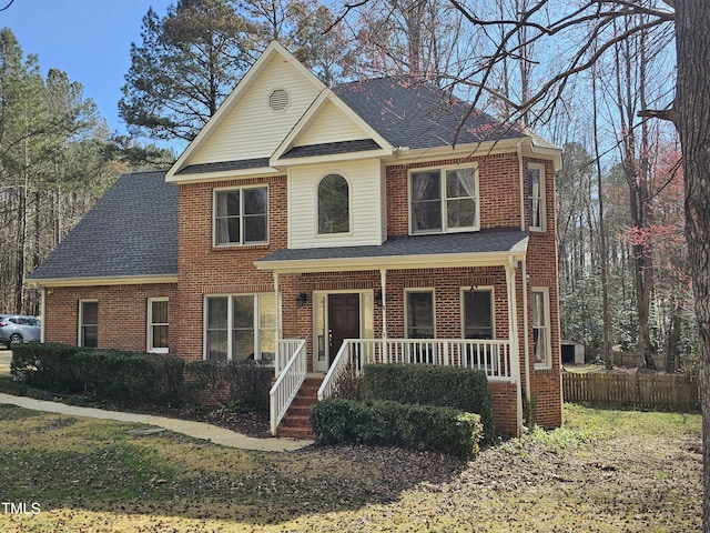 view of front of home with a porch, brick siding, and a shingled roof