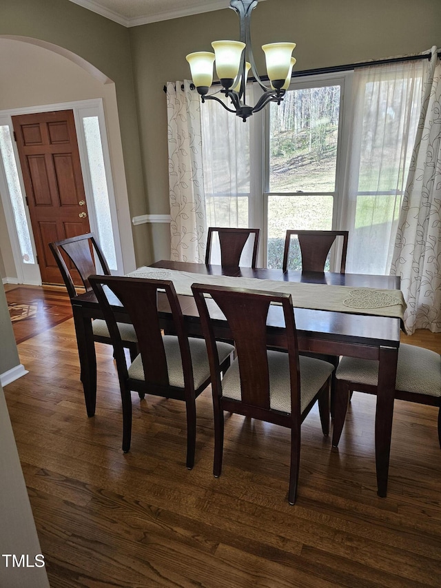 dining room featuring arched walkways, an inviting chandelier, dark wood finished floors, and crown molding