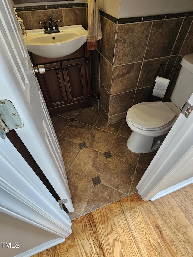 half bathroom with vanity, tile walls, and toilet