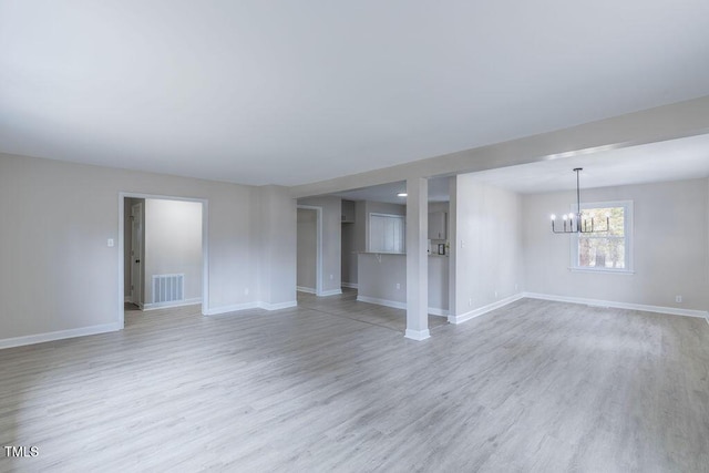 unfurnished living room featuring a chandelier, light wood-type flooring, visible vents, and baseboards