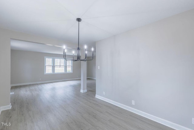 unfurnished dining area with an inviting chandelier, baseboards, and wood finished floors