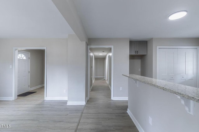 hall with light wood-style floors and baseboards