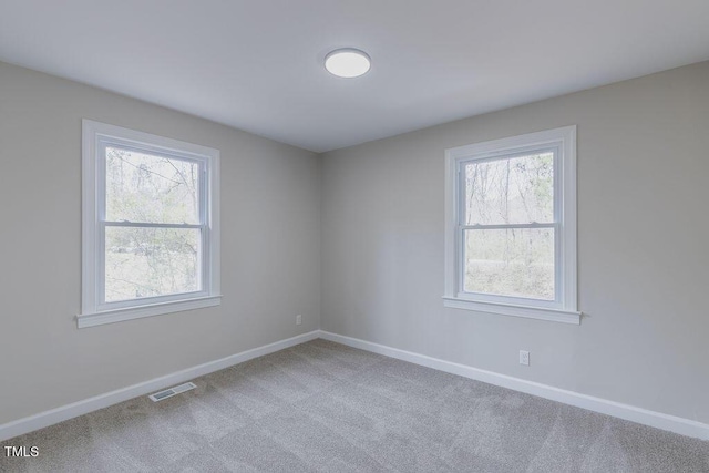 carpeted spare room with visible vents and baseboards