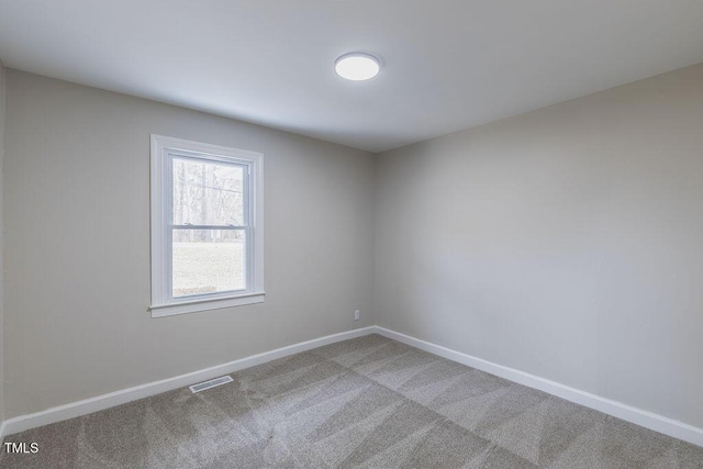 spare room featuring carpet floors, visible vents, and baseboards