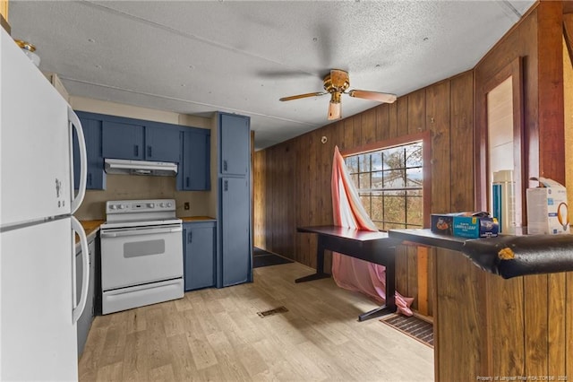 kitchen with light wood-style flooring, blue cabinets, wooden walls, under cabinet range hood, and white appliances