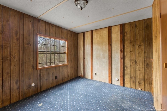 carpeted spare room with wood walls