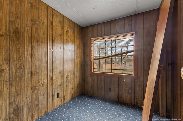 spare room with carpet and wooden walls