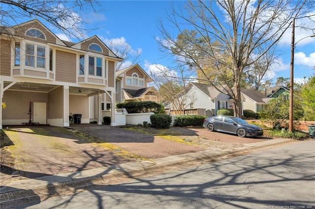 view of front facade with driveway, a residential view, fence, and a carport