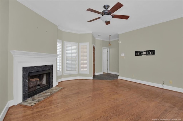 unfurnished living room featuring baseboards, a ceiling fan, a premium fireplace, ornamental molding, and wood finished floors