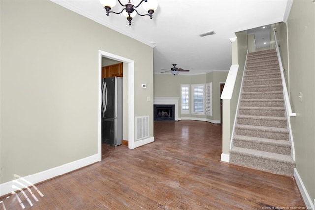 unfurnished living room with ornamental molding, visible vents, stairway, and wood finished floors