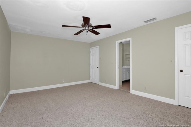 unfurnished bedroom featuring light colored carpet, a ceiling fan, baseboards, visible vents, and ensuite bath