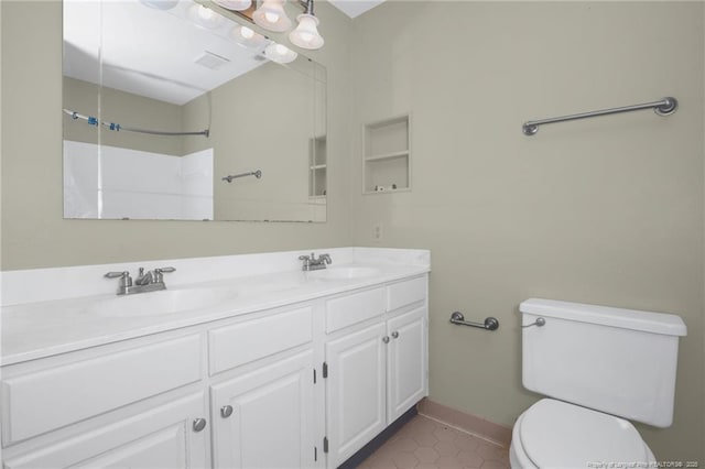 bathroom featuring toilet, double vanity, baseboards, and a sink