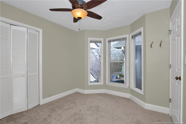 unfurnished bedroom with ceiling fan, carpet floors, a closet, and baseboards