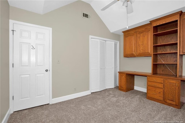 unfurnished office featuring lofted ceiling, built in desk, carpet, and visible vents