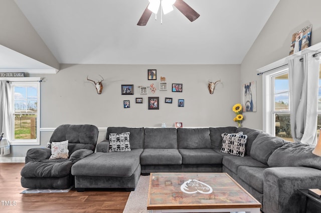 living area featuring a ceiling fan, lofted ceiling, baseboards, and wood finished floors