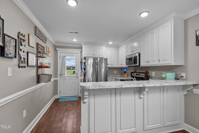 kitchen featuring dark wood-style flooring, stainless steel appliances, white cabinetry, a peninsula, and baseboards