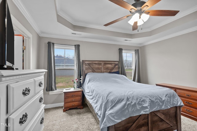 bedroom featuring light carpet, visible vents, multiple windows, and a tray ceiling