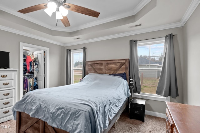 bedroom featuring a tray ceiling, multiple windows, carpet flooring, and visible vents