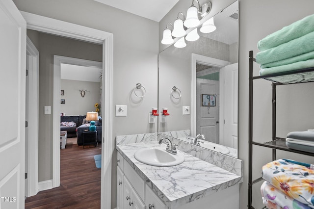 bathroom with a notable chandelier, wood finished floors, visible vents, baseboards, and vanity