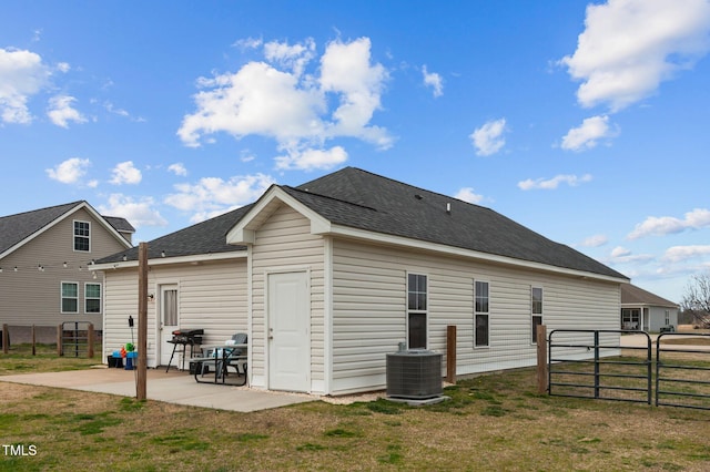 back of house with a shingled roof, fence, a patio, and a yard