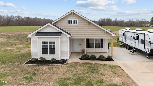 view of front facade featuring a porch, board and batten siding, a front yard, and a shingled roof