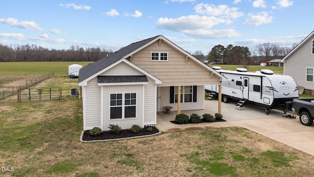 view of front of home with a shingled roof, fence, driveway, and a front lawn