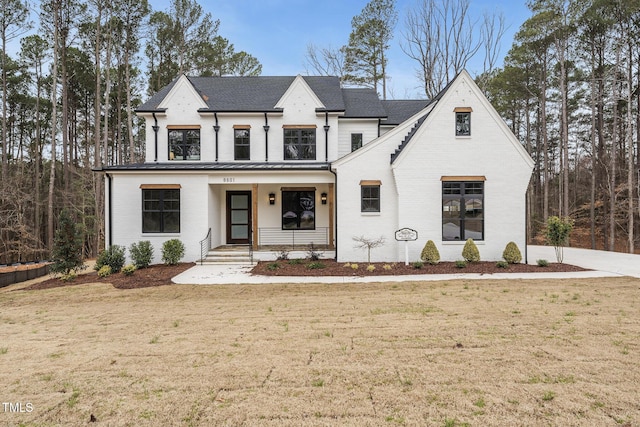 view of front of house featuring a porch, a front lawn, and brick siding