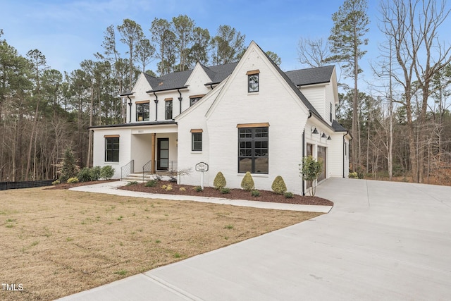 view of front of home with a garage, concrete driveway, brick siding, and a front lawn