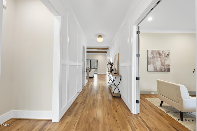 hallway featuring crown molding, light wood-style flooring, and baseboards