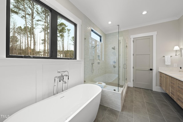 bathroom featuring tile patterned floors, crown molding, vanity, a freestanding tub, and a shower stall