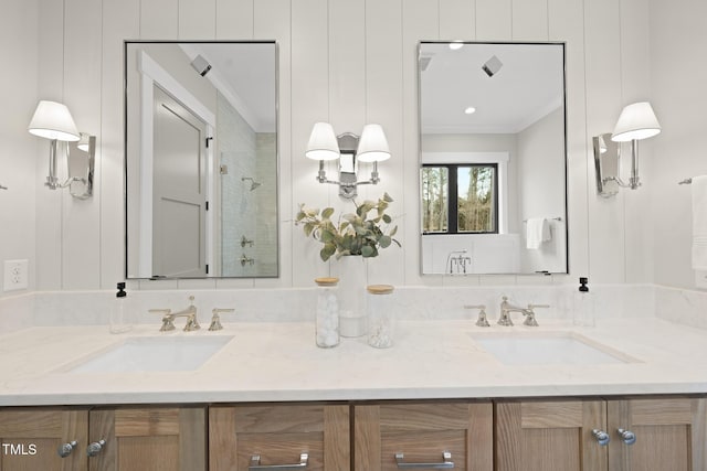 full bath with double vanity, a stall shower, crown molding, and a sink