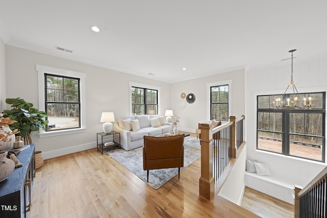 living area featuring ornamental molding, an inviting chandelier, visible vents, and light wood-style floors