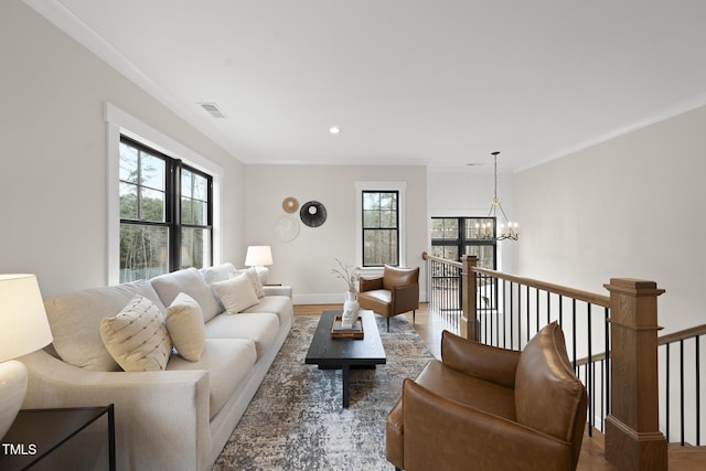 living room with ornamental molding, visible vents, a notable chandelier, and wood finished floors