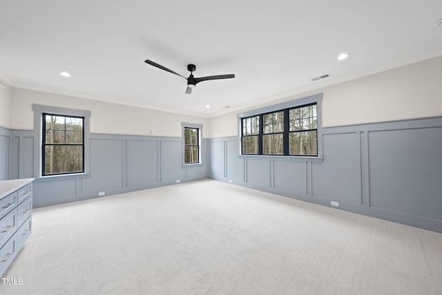 unfurnished room with a wainscoted wall, ornamental molding, and light colored carpet