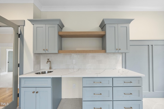 kitchen featuring light stone countertops, a sink, backsplash, and open shelves